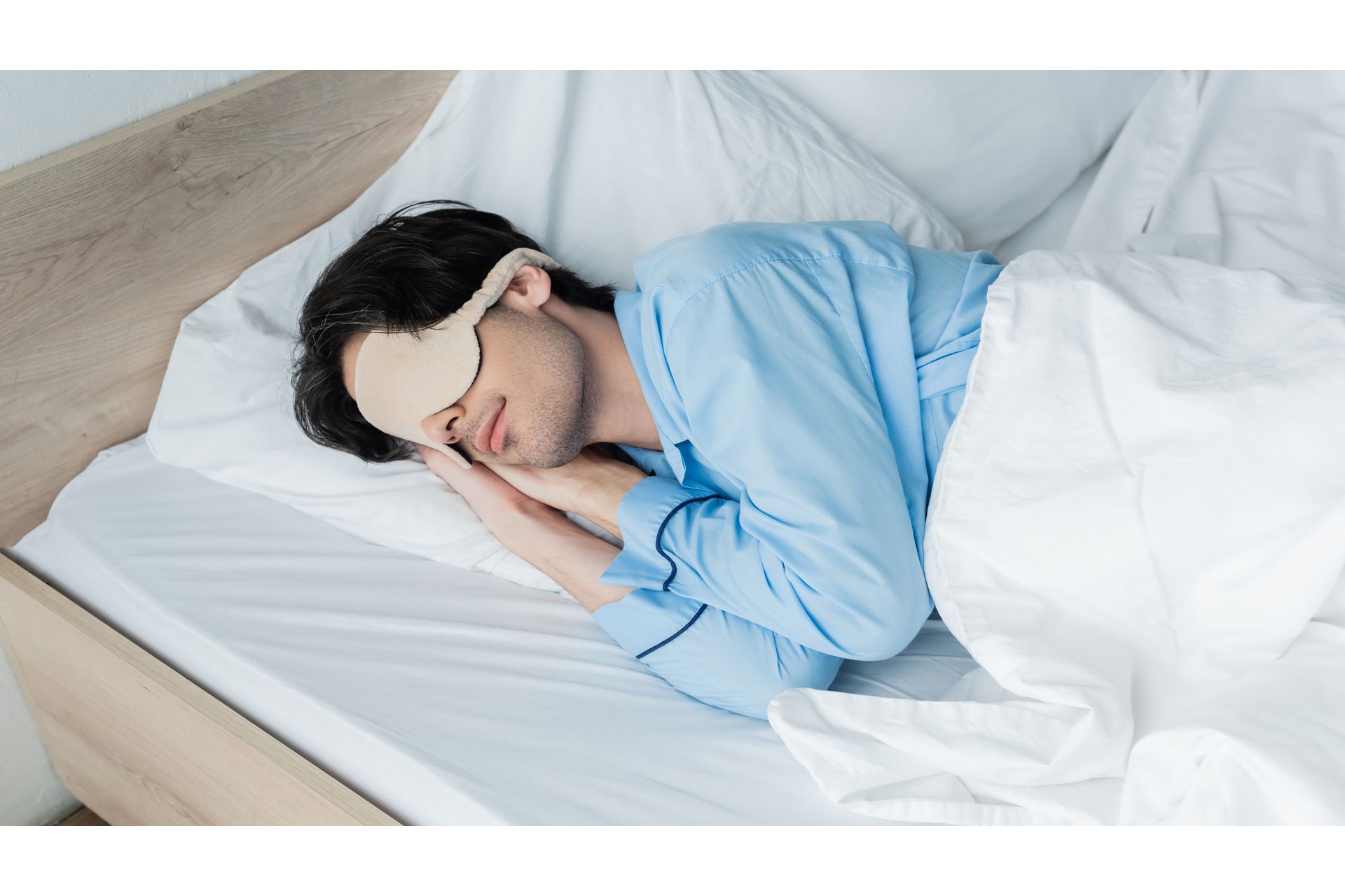 young-man-in-sleep-mask-and-pajamas-sleeping-on-wh-2023-11-27-05-02-49-utc--1-