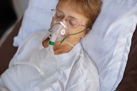 senior-female-patient-in-a-breathing-mask-lies-in-2024-10-18-08-15-12-utc--1-